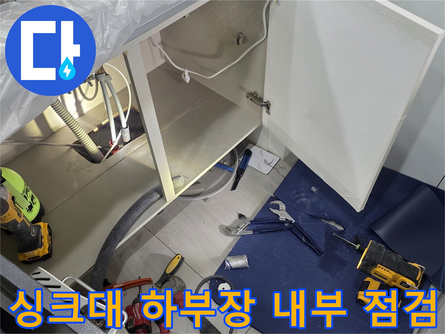 주방 싱크대 아래 배관 구조와 작업용 전동 드릴 배치