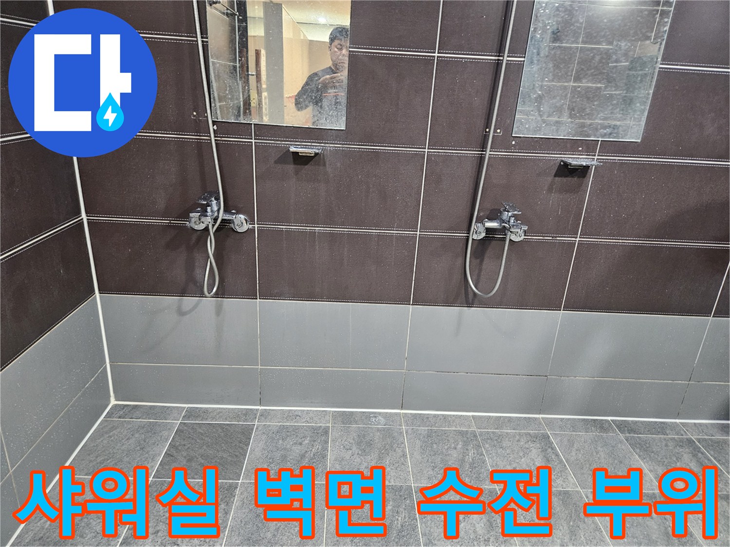어두운색 타일과 금속 재질의 샤워 수전 상세 모습
