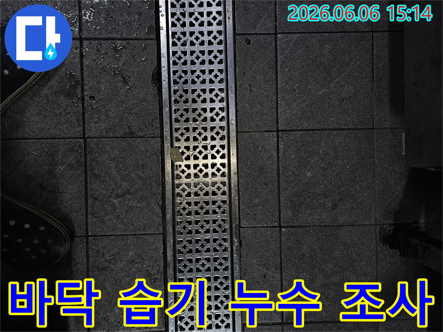 젖은 타일과 배수구가 있는 어두운 공간-누수 문제로 인한 물기 확인-전문가가 현장 상황을 파악하는 모습
