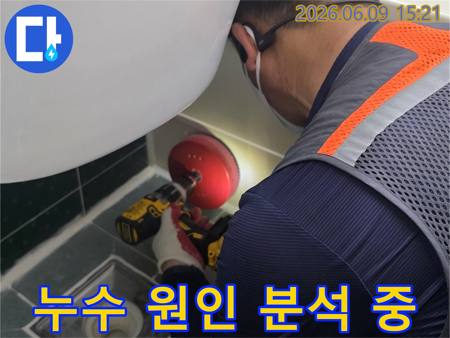 안전-조끼를-입은-전문가가-욕실-배수구-근처의-누수-지점을-정확히-파악하기-위해-전동-공구를-사용하여-작업하는-장면