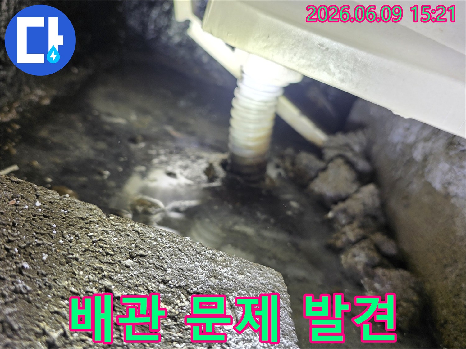 어두운 곳에서-플래시로 비춘-배관 하부의-고인 물과-누수 흔적