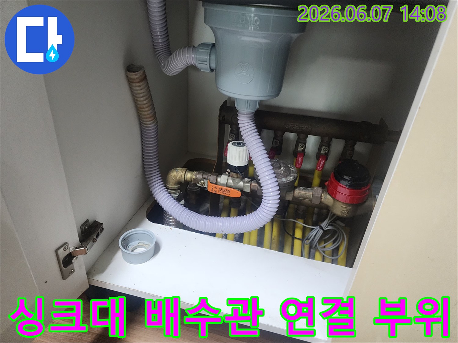 주름관을 제거하기 위해 싱크대 하부의 배수 밸브와 호스를 점검하는 장면입니다.