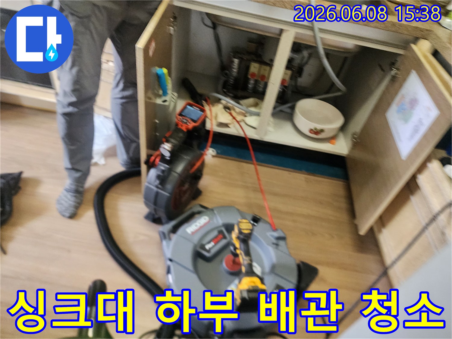 싱크대 아래 배관의 이물질을 제거하기 위해 장비를 가동하는 모습입니다.