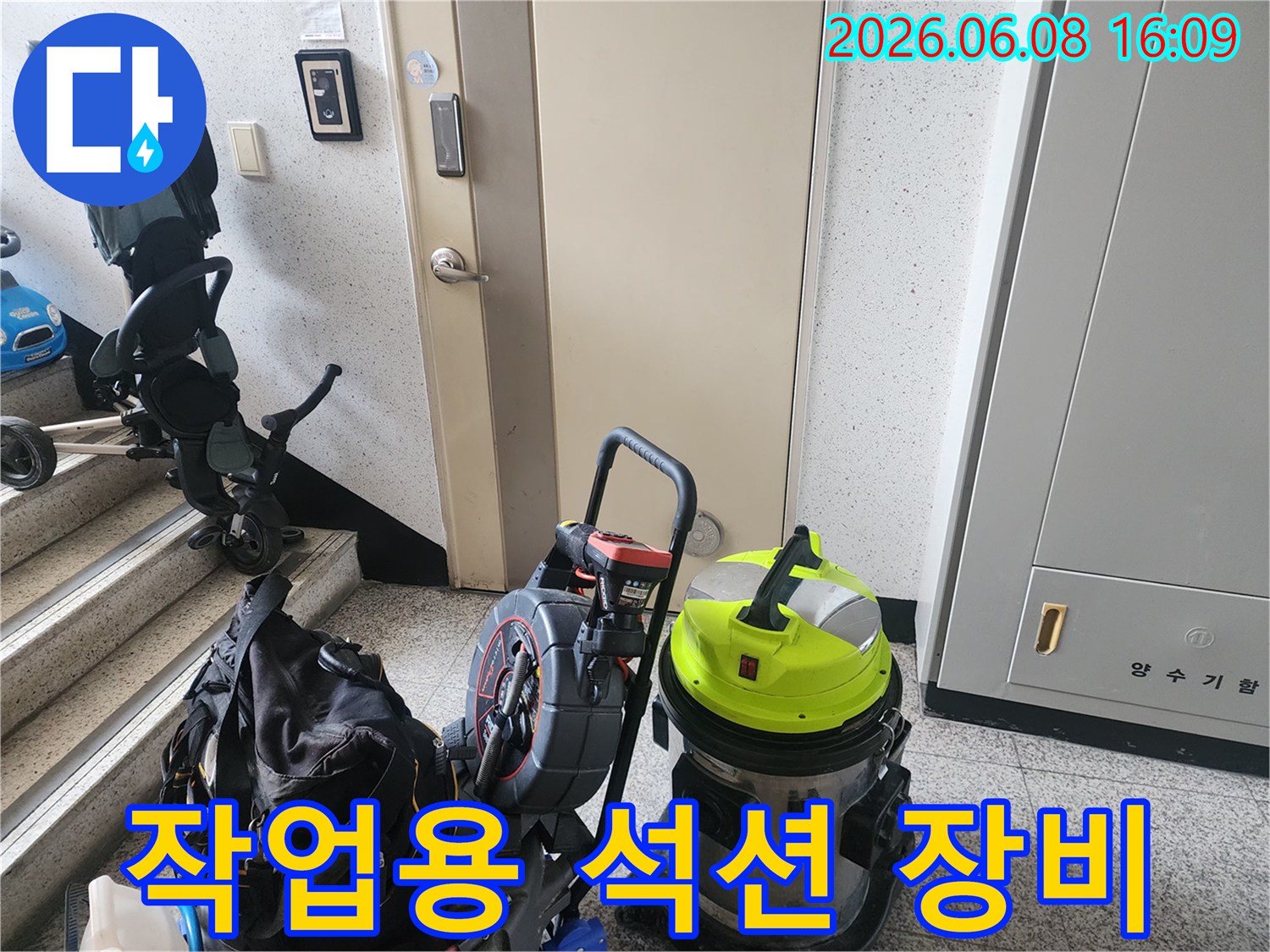 계단 입구에 놓인 노란색 석션기와 배관 작업 도구