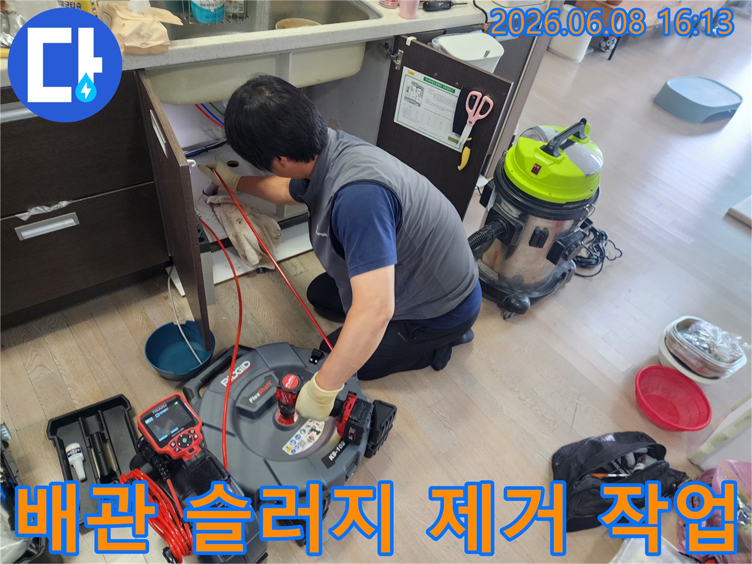 싱크대 배관 내부의 찌꺼기를 제거하기 위해 장비를 운용하는 장면입니다.
