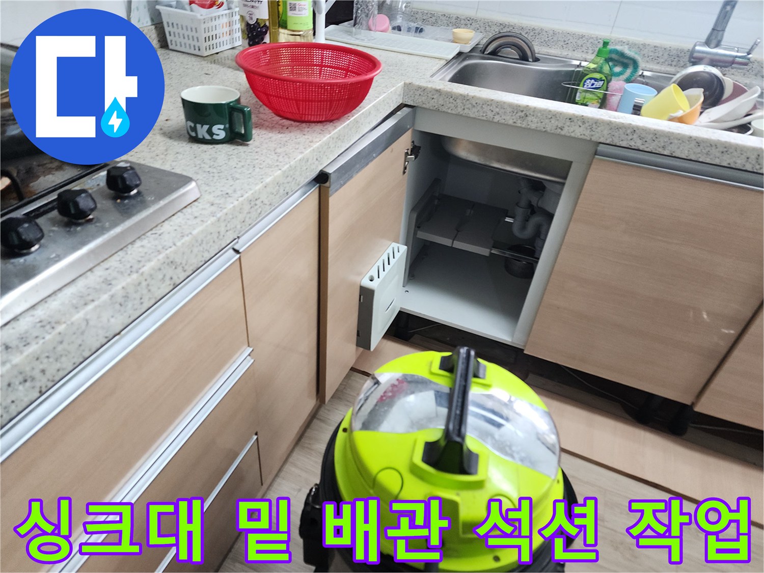 하부장 내부의 노출된 배수 파이프와 작동 중인 석션기