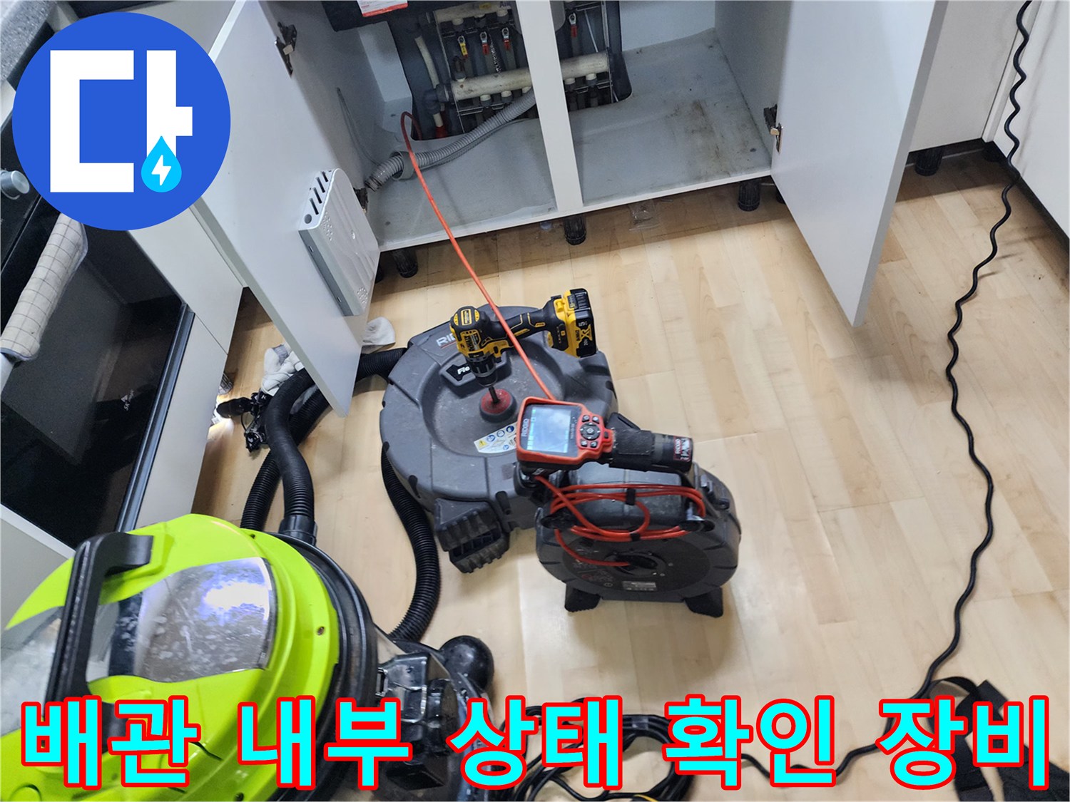 작업 중인 싱크대 하부장 아래의 내시경 모니터와 전동 드릴 장비