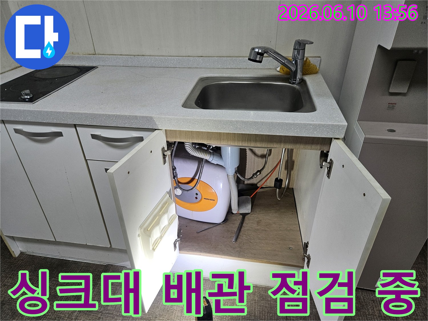 싱크대 밑 물고임의 원인을 찾기 위해-배관과 온수기를-세밀하게 점검하고 있습니다.