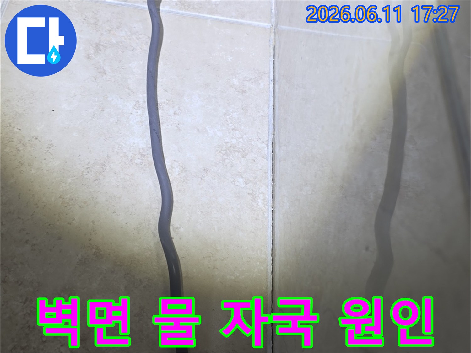 욕실 벽면 타일 하단부에-물이 스며들어 습기가 올라온 현장을 보여주는 사진입니다