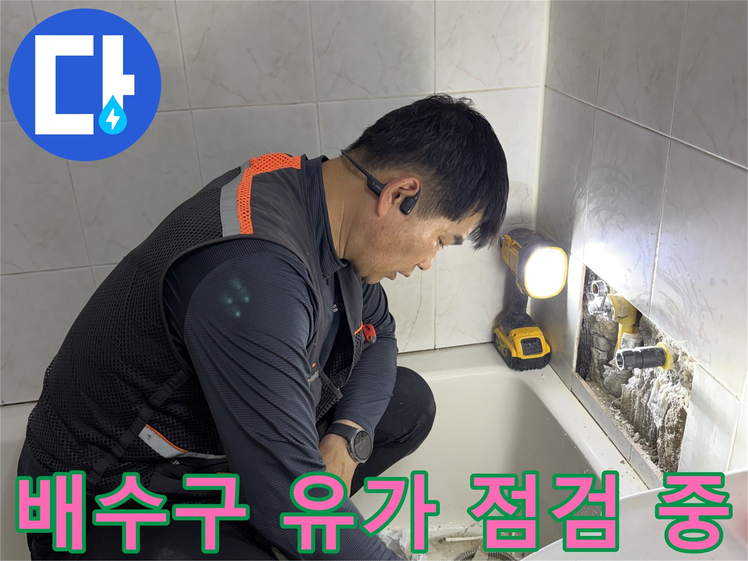 화장실 배수구 주변의 방수 결함을 조사하고 있는 엔지니어