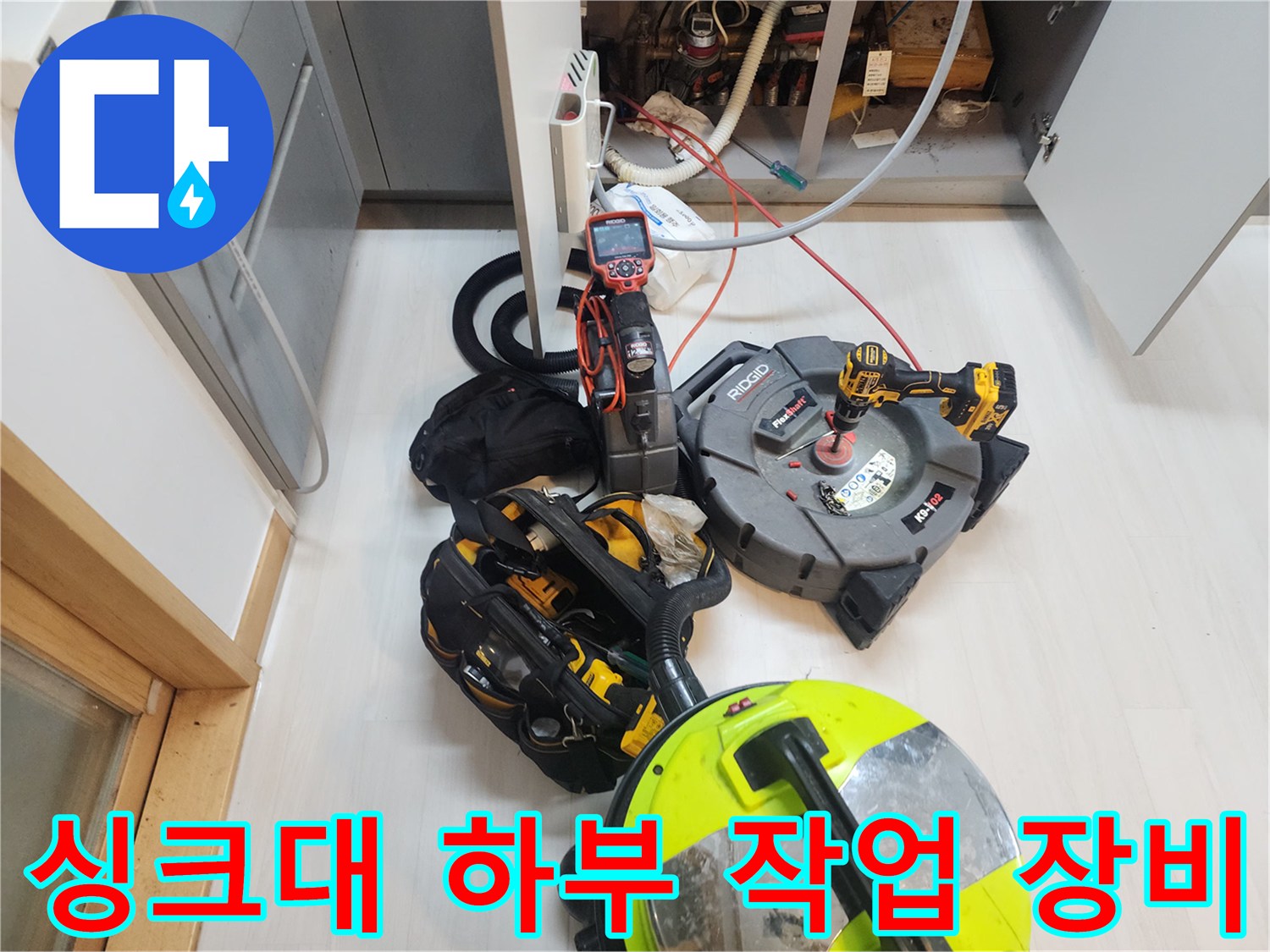 주방 싱크대 하부 배관 작업을 위해 준비된 전문 스케일링 장비와 석션기