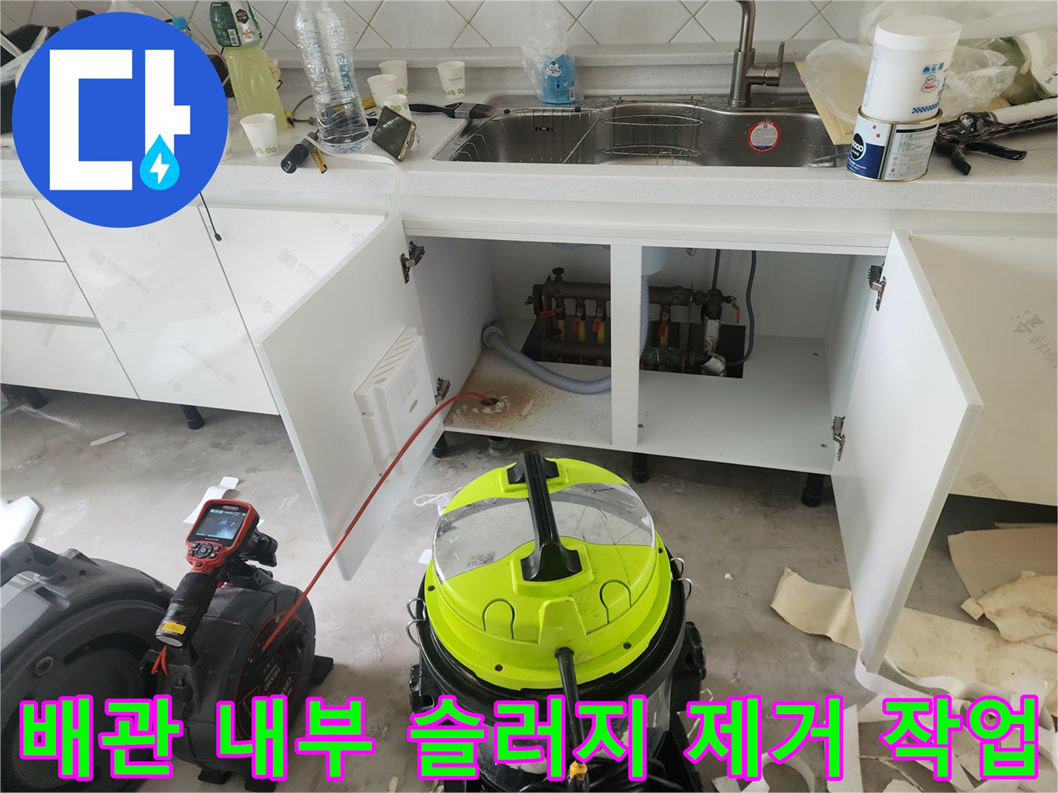주방 싱크대 아래쪽 배관의 오염 상태와 청소 장비 배치