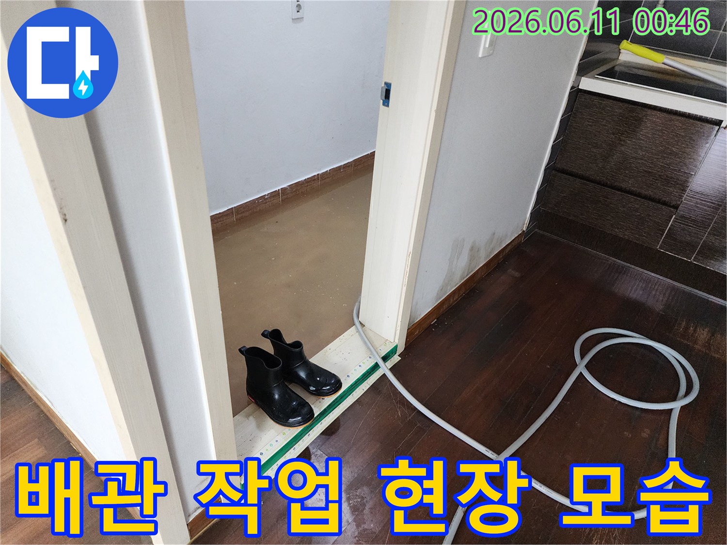 화장실 문턱 아래 젖은 바닥과 길게 늘어진 배관 세척 호스