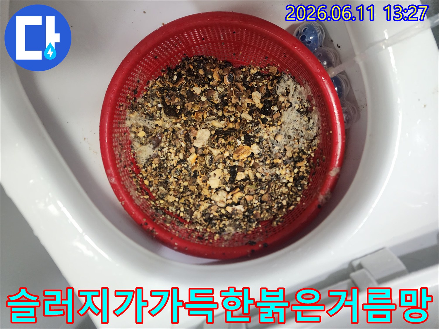 붉은색 거름망에 모인 배관 내부의 오염된 슬패 찌꺼기