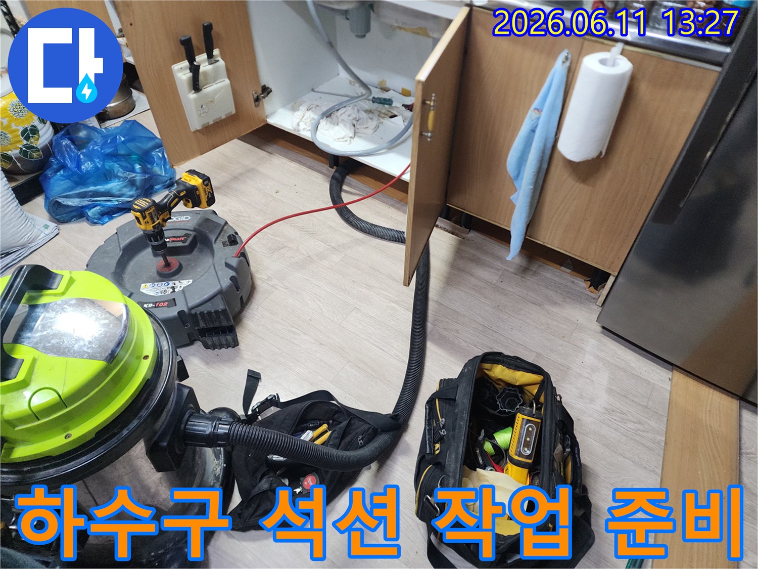 싱크대 배수관 청소를 위해 석션기와 공구 가방을 배치한 하부장 내부 모습입니다.
