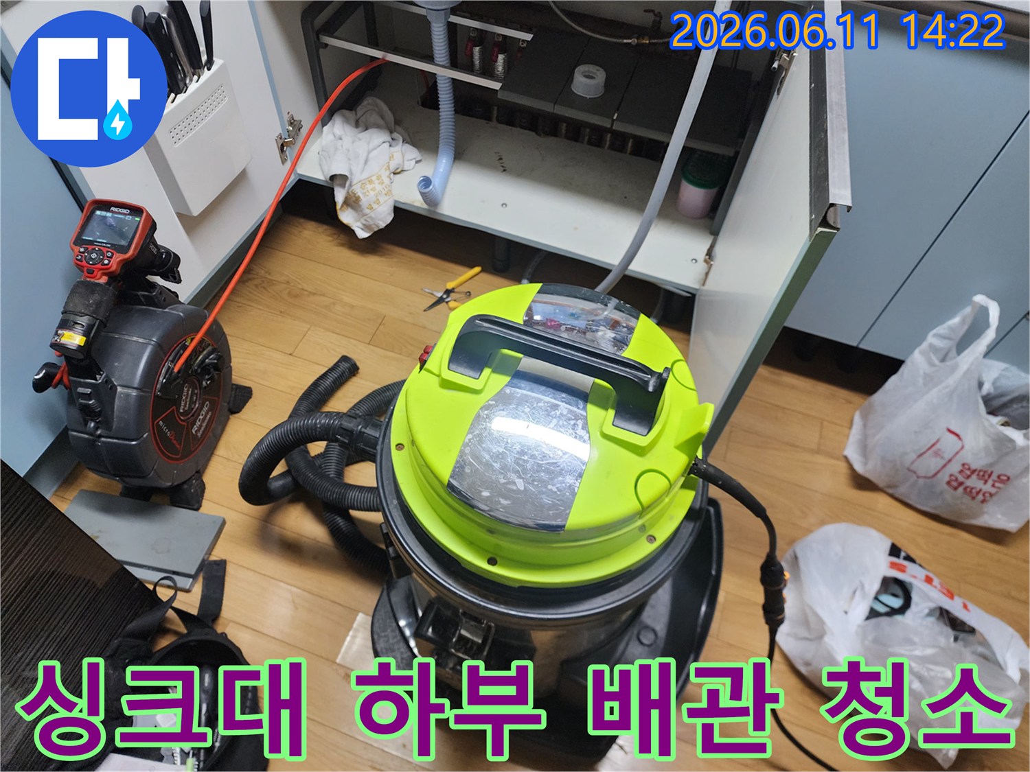 싱크대 아래 배수관에 쌓인 오염물을 제거하기 위해 석션기를 사용하는 모습입니다.