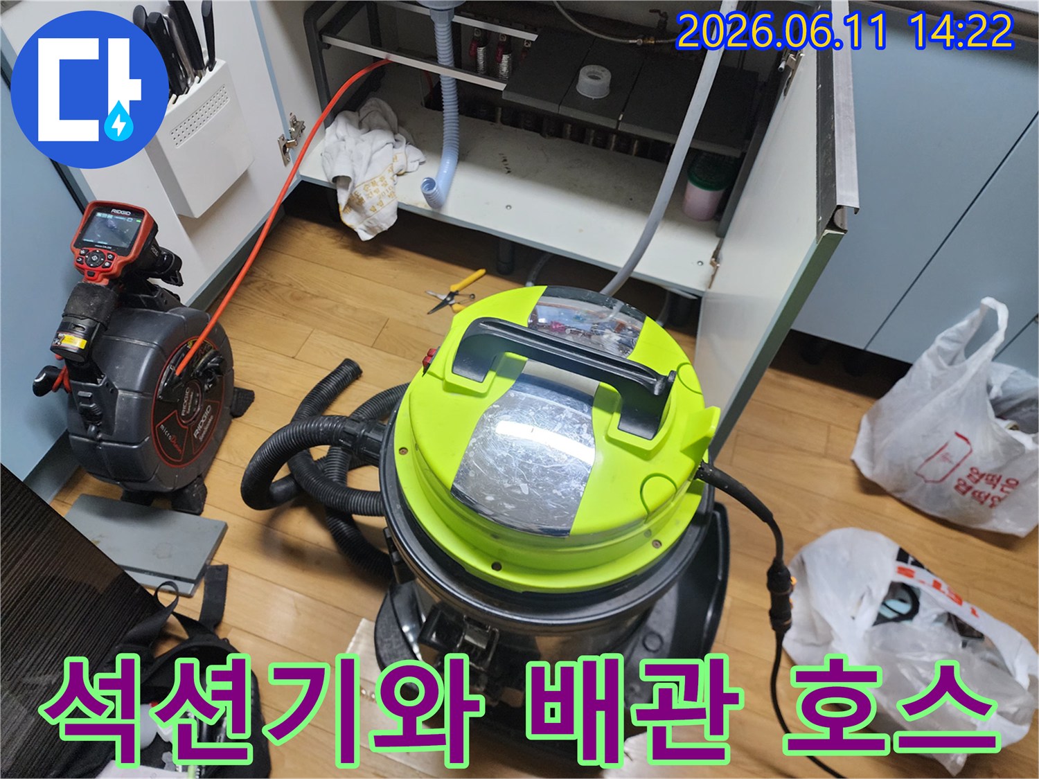 싱크대 하부장 내부의 배관 청소를 위해 배치된 석션기와 흡입용 호스 모습입니다.