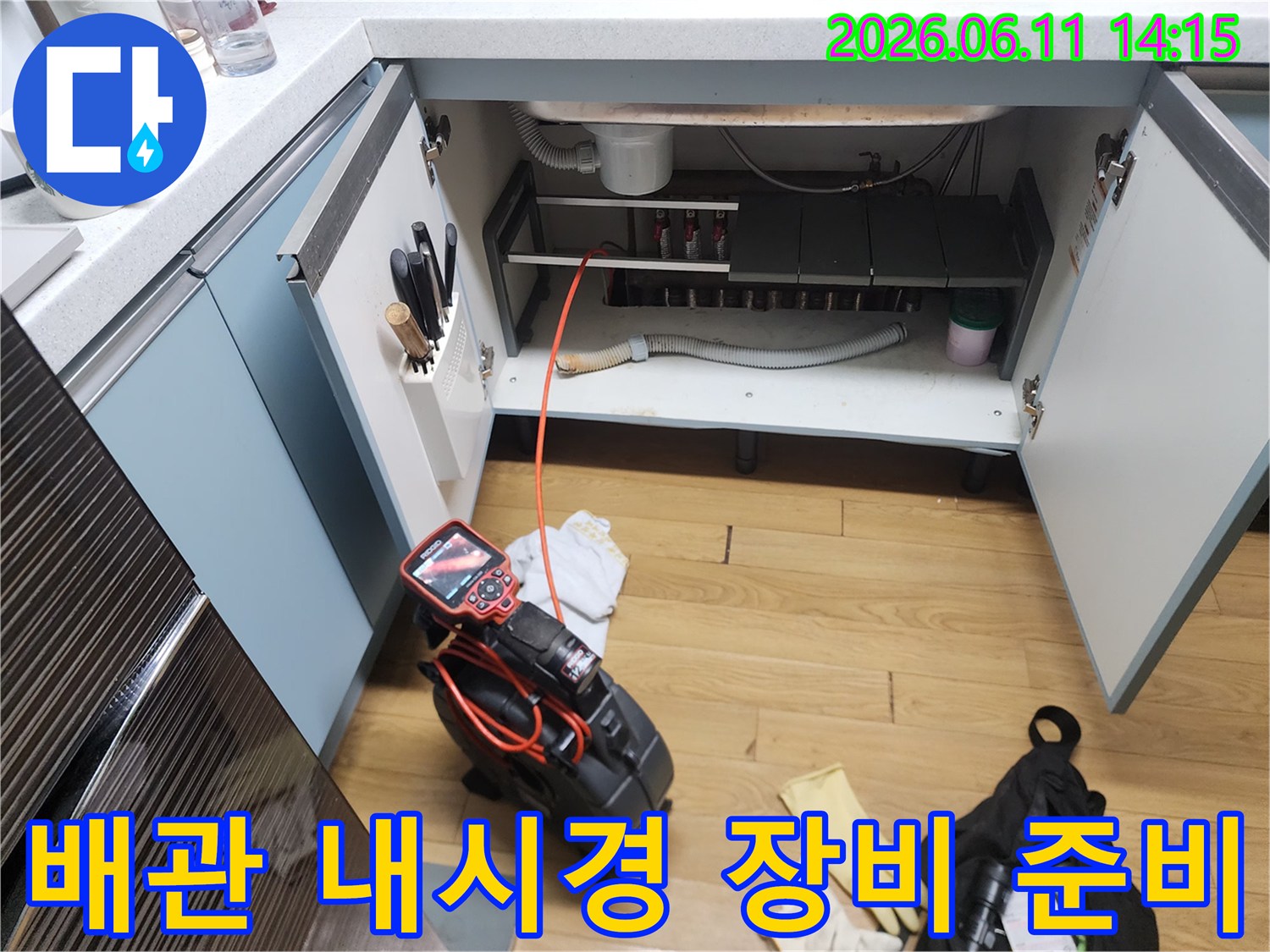 작업을 위해 싱크대 하부장에 배치된 배관 내시경 장비와 호스입니다.