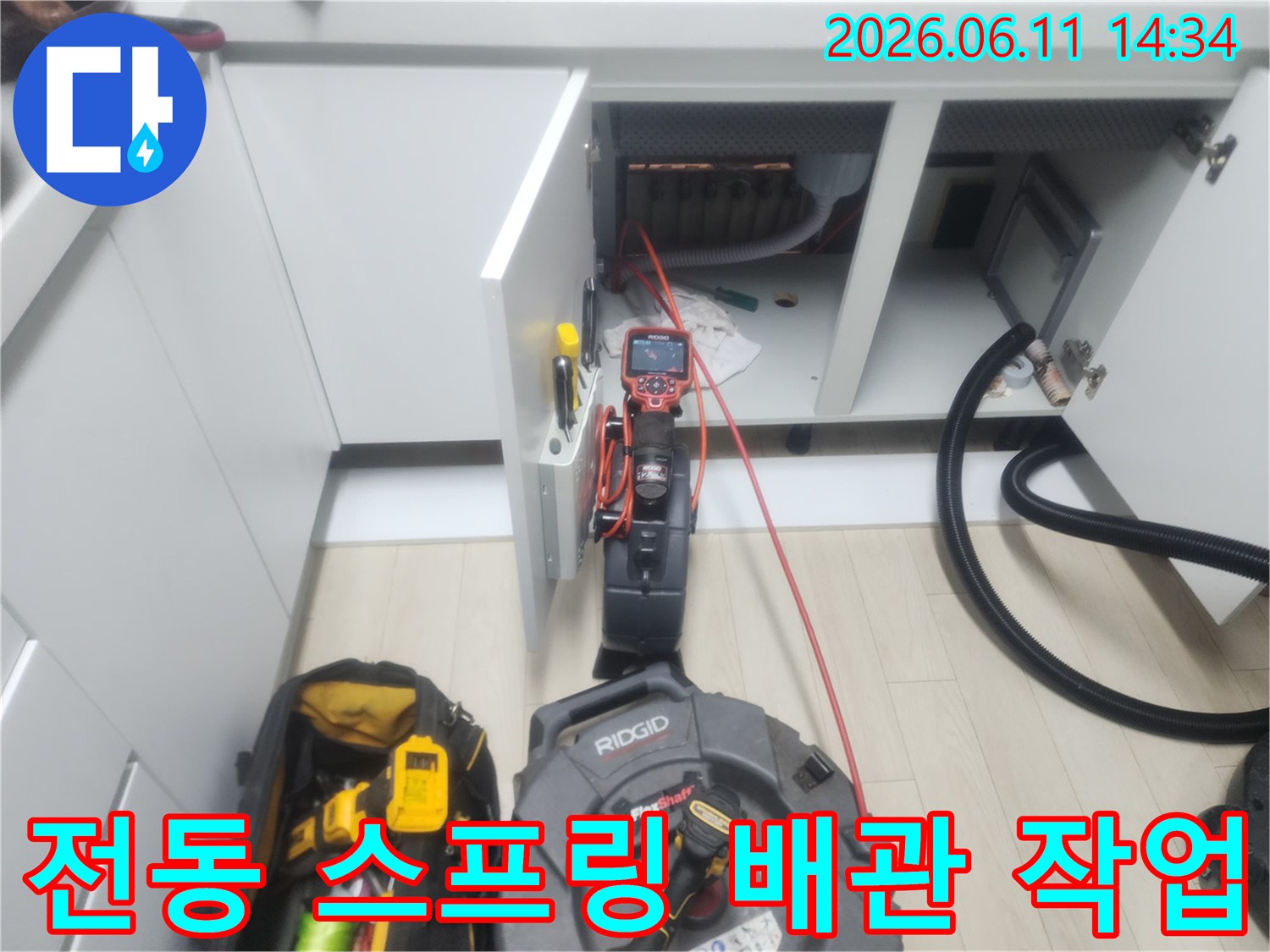 싱크대 하부장 배관 내부의 오물을 제거하기 위해 작동 중인 전동 장비