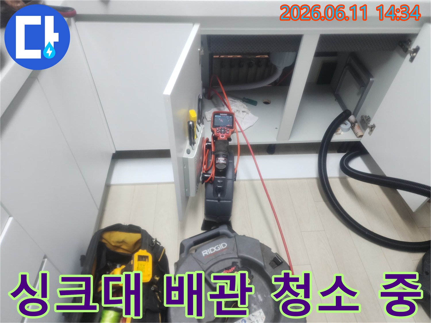 하부장 깊숙한 곳의-배관을 청소하기 위해-장비를 투입하고 있는 작업 현장입니다.