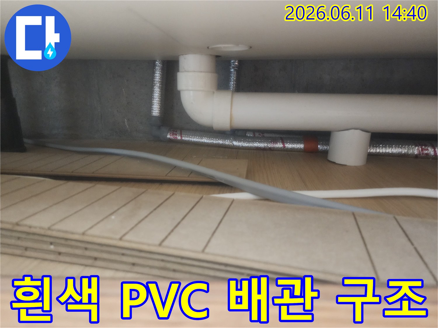싱크대 하부의 흰색 배수 파이프와 은색 보온재 마감 상태