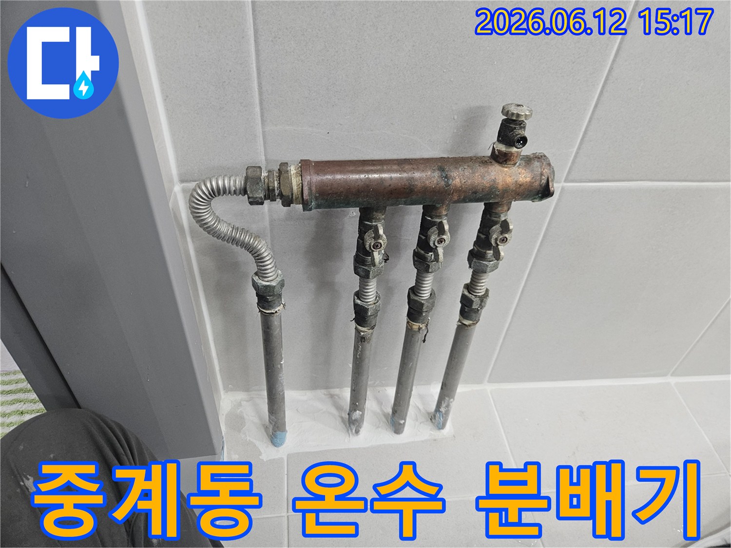 중계동 아파트의 온수 배관 분배기에서 누수 징후가 포착되어-전문가가 노후된 배관과 밸브 상태를 꼼꼼히 확인하고 있습니다