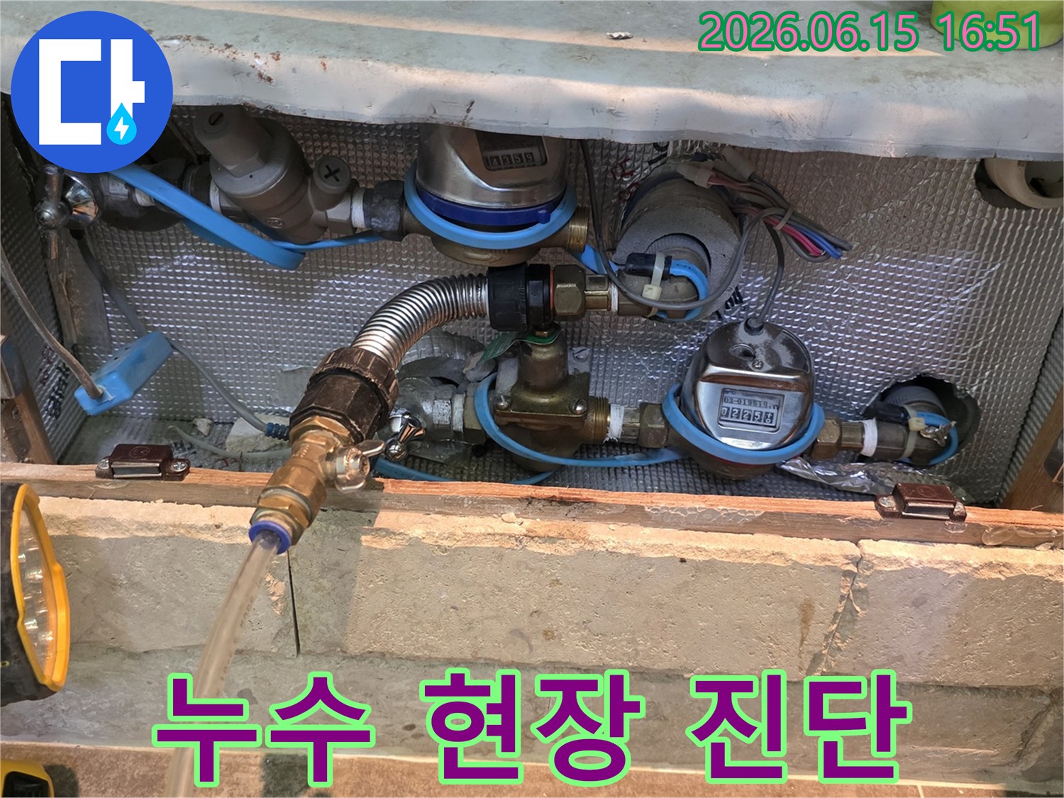 누수 진단을 위해 배관에 연결된 유연한 금속 호스와 투명한 배출 호스-정확한 누수 위치를 파악하기 위한 전문적인 장비 사용 모습입니다.