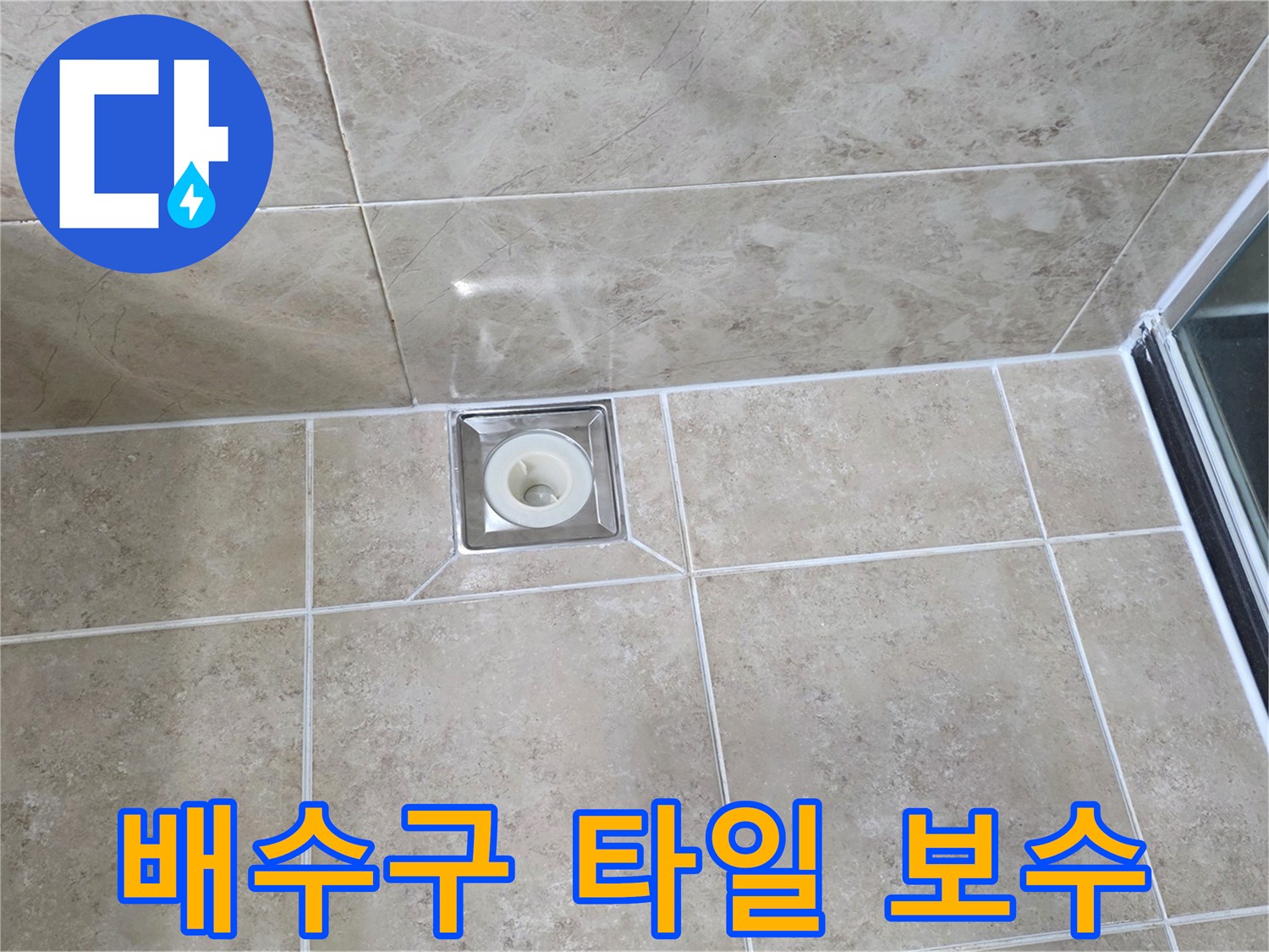 베이지색 타일 바닥에 위치한-사각형 금속 배수구의 모습으로-주변 타일의 접합부와-줄눈의 상태를 상세히 보여줍니다