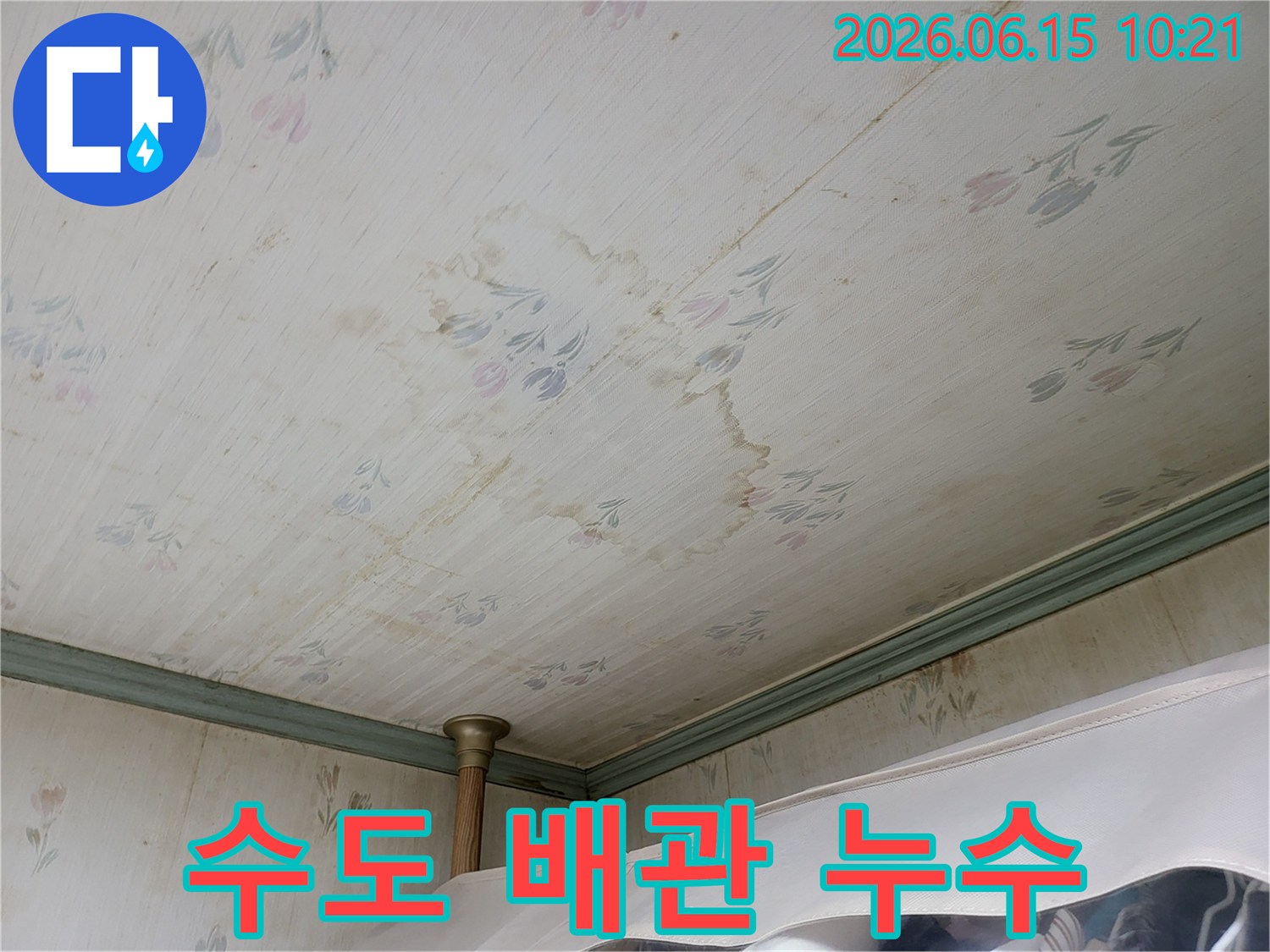 천장 벽지에 생긴-물얼룩과-변색이-수도 배관 누수로 인한 것임을-시사하는 사진입니다
