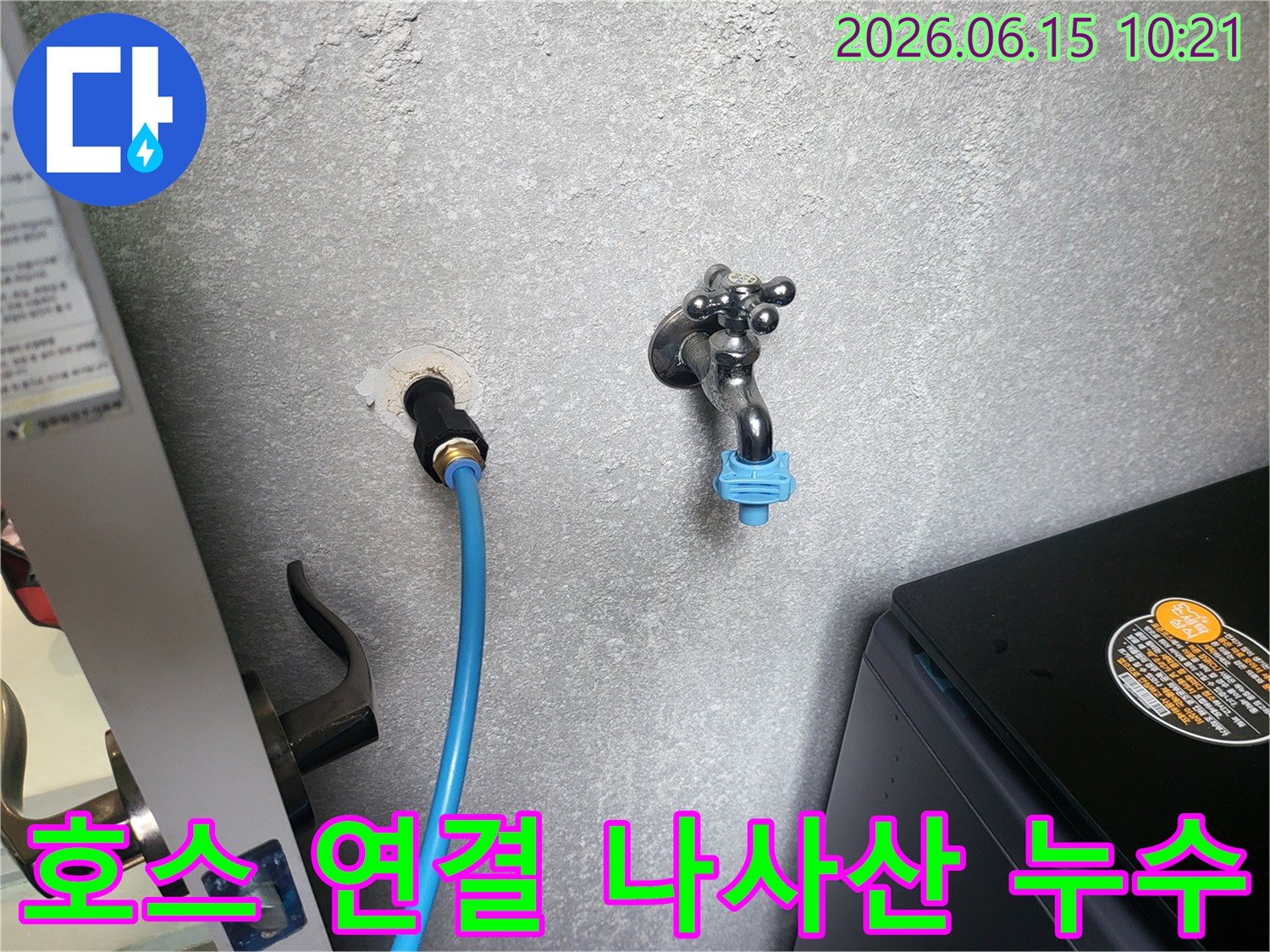 회색 벽에 연결된 파란색 수도 호스-연결 나사산 부분에서 발생한 누수를 점검하는 모습