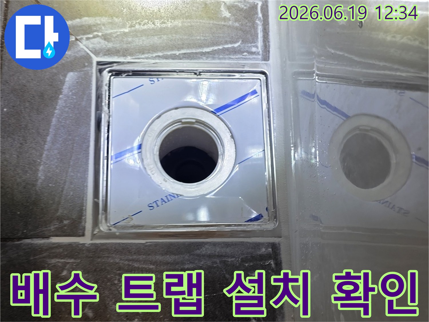 스테인리스 보호 커버가 덮인 채-욕실 바닥에 설치될 배수 트랩의 정밀한 위치를 보여주는 사진