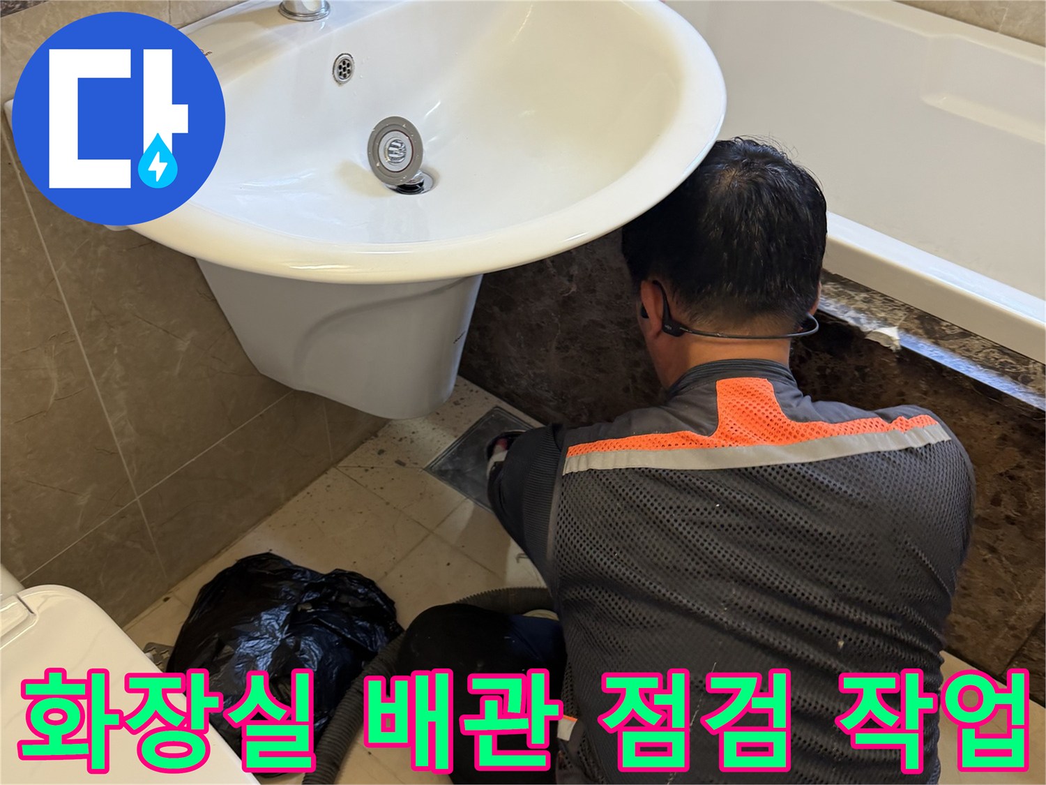 엔지니어가 화장실 세면대 아래 배수구 주변을 정밀하게 살피고 있습니다