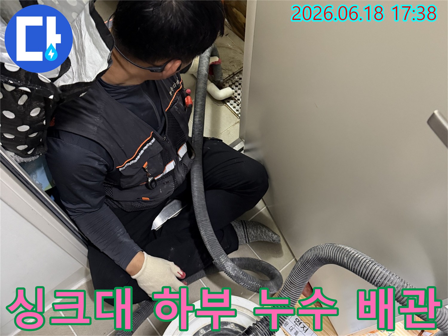 이 사진은-싱크대 하부의-좁은 공간에서-누수 배관을-점검하고-수리하는-전문가의-모습을-담고 있습니다