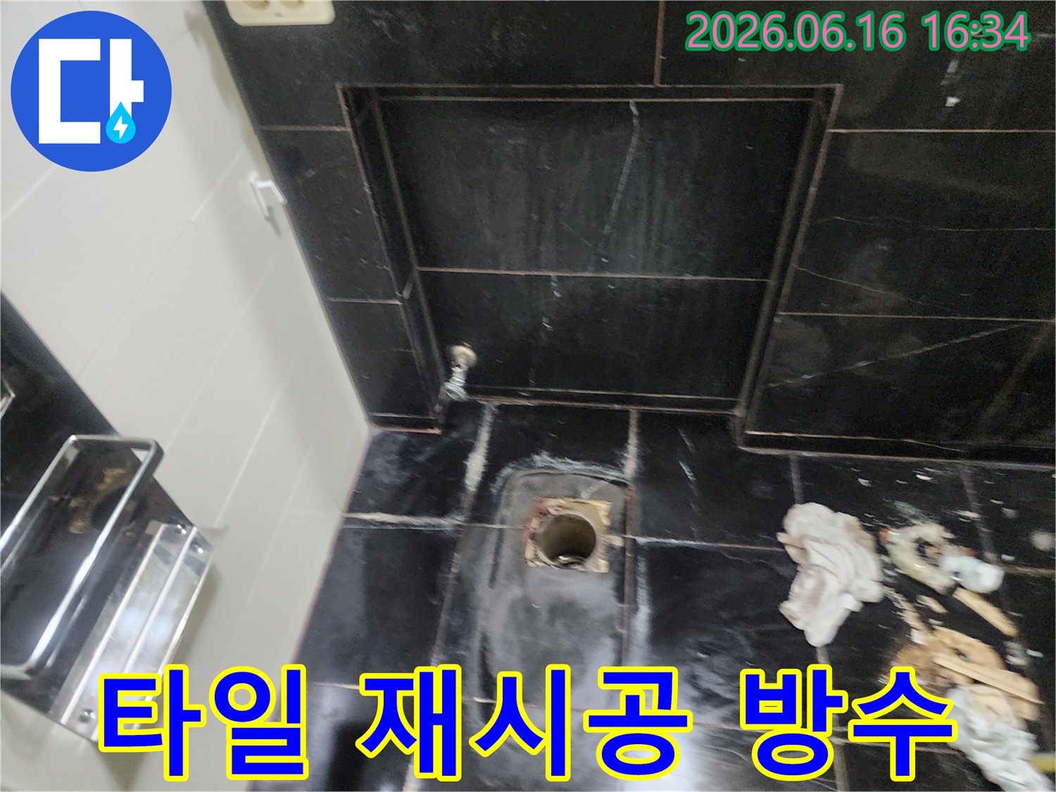 검은색 타일 바닥의 배관 구멍 주변에서 누수 흔적을 확인하고 타일 재시공 및 방수 작업을 준비하는 모습입니다.