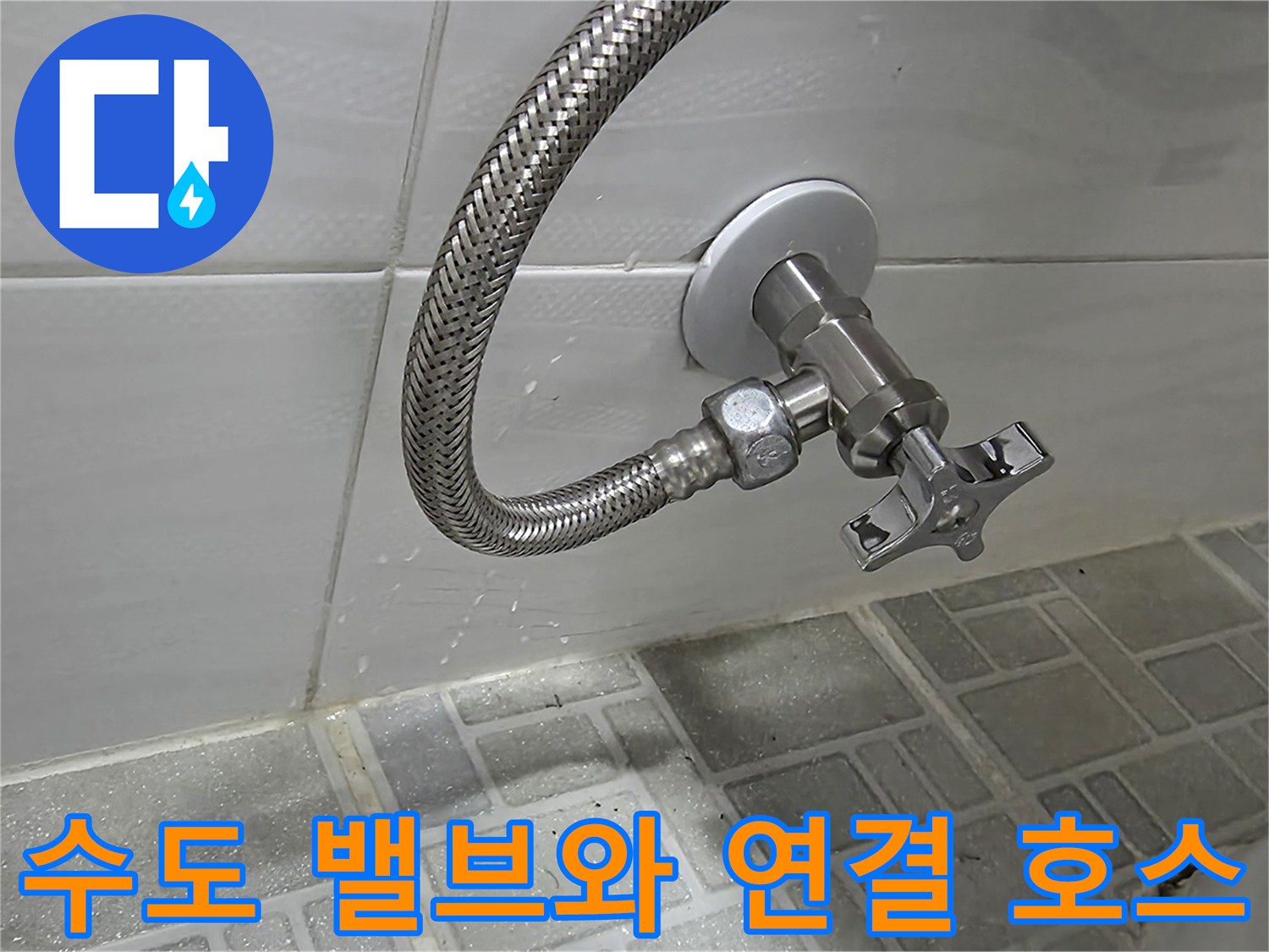 벽면 타일과 수도 밸브, 은색 호스가 보이는 욕실 내부 사진