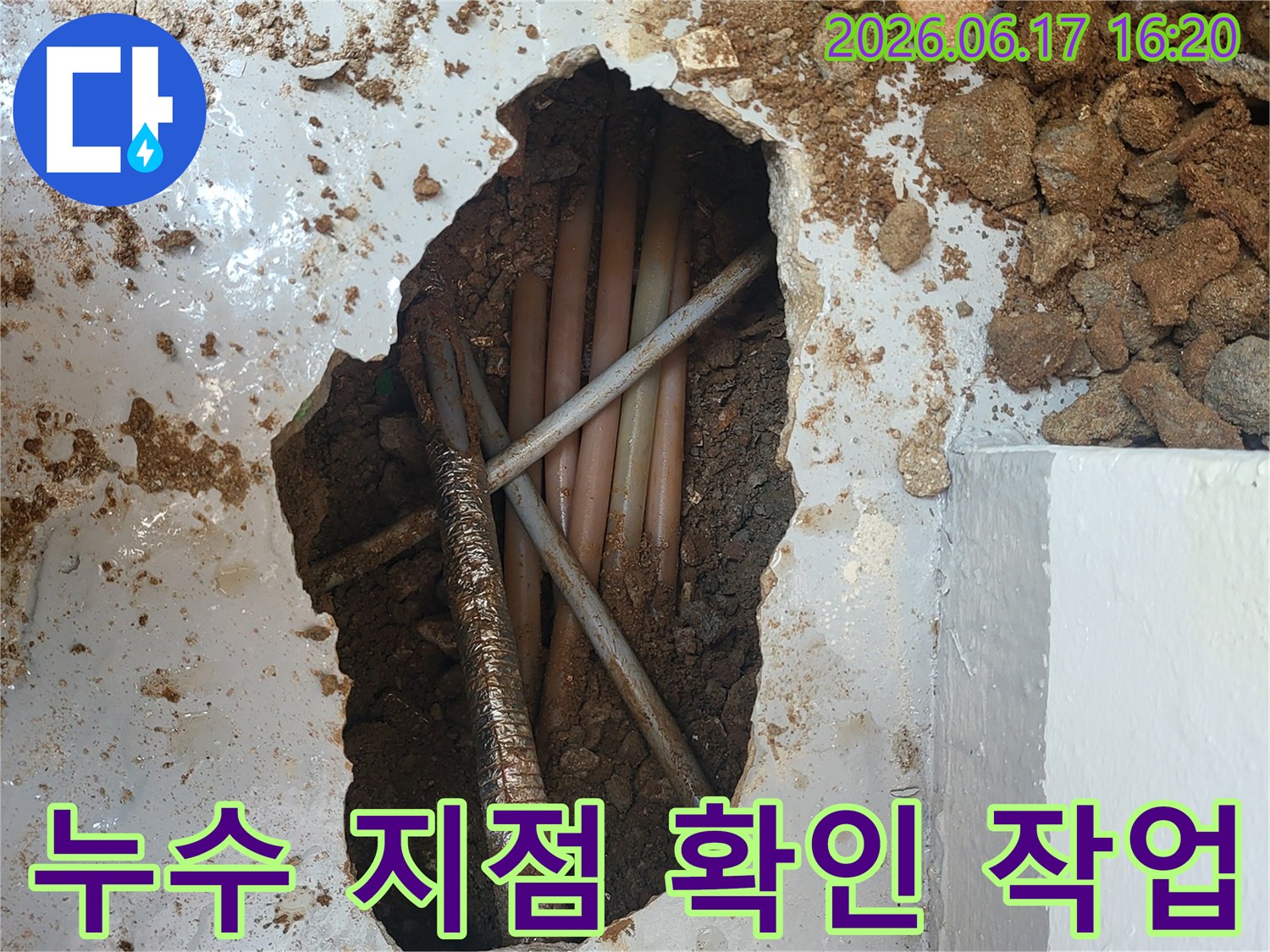 이 사진은 누수 지점을 확인하기 위해-콘크리트 바닥을 깨고 매설된 배관들을 점검하는-누수 공사 현장의 모습입니다.
