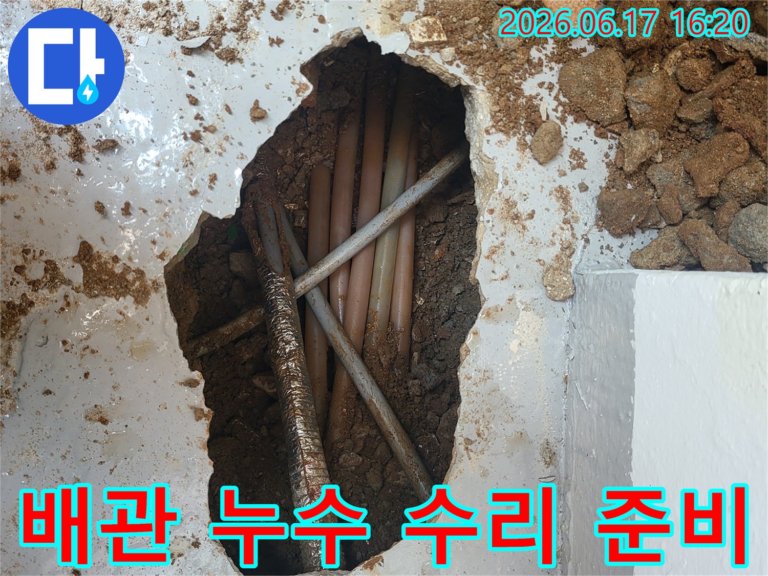 이 사진은 누수 지점을 확인하기 위해-콘크리트 바닥을 깨고 매설된 배관들을 점검하는-누수 공사 현장의 모습입니다.