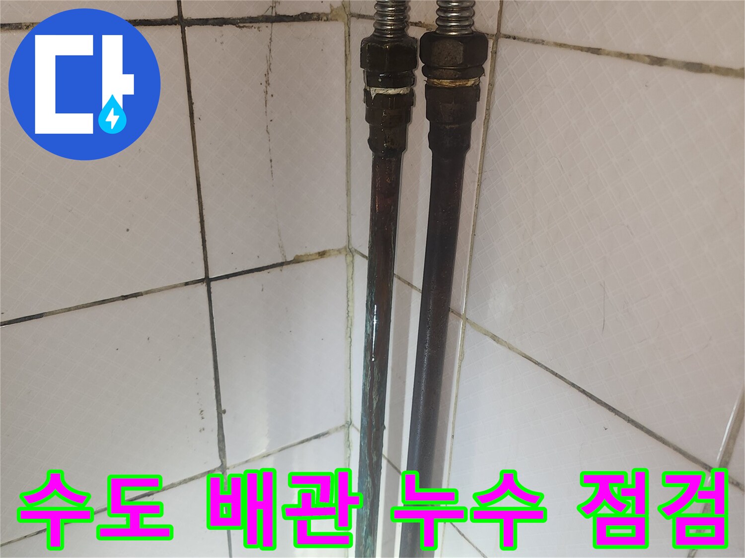 오래된 수도 배관의 연결 부위와 주변 타일의 상태를 보여주며-누수 점검 과정을 나타냅니다