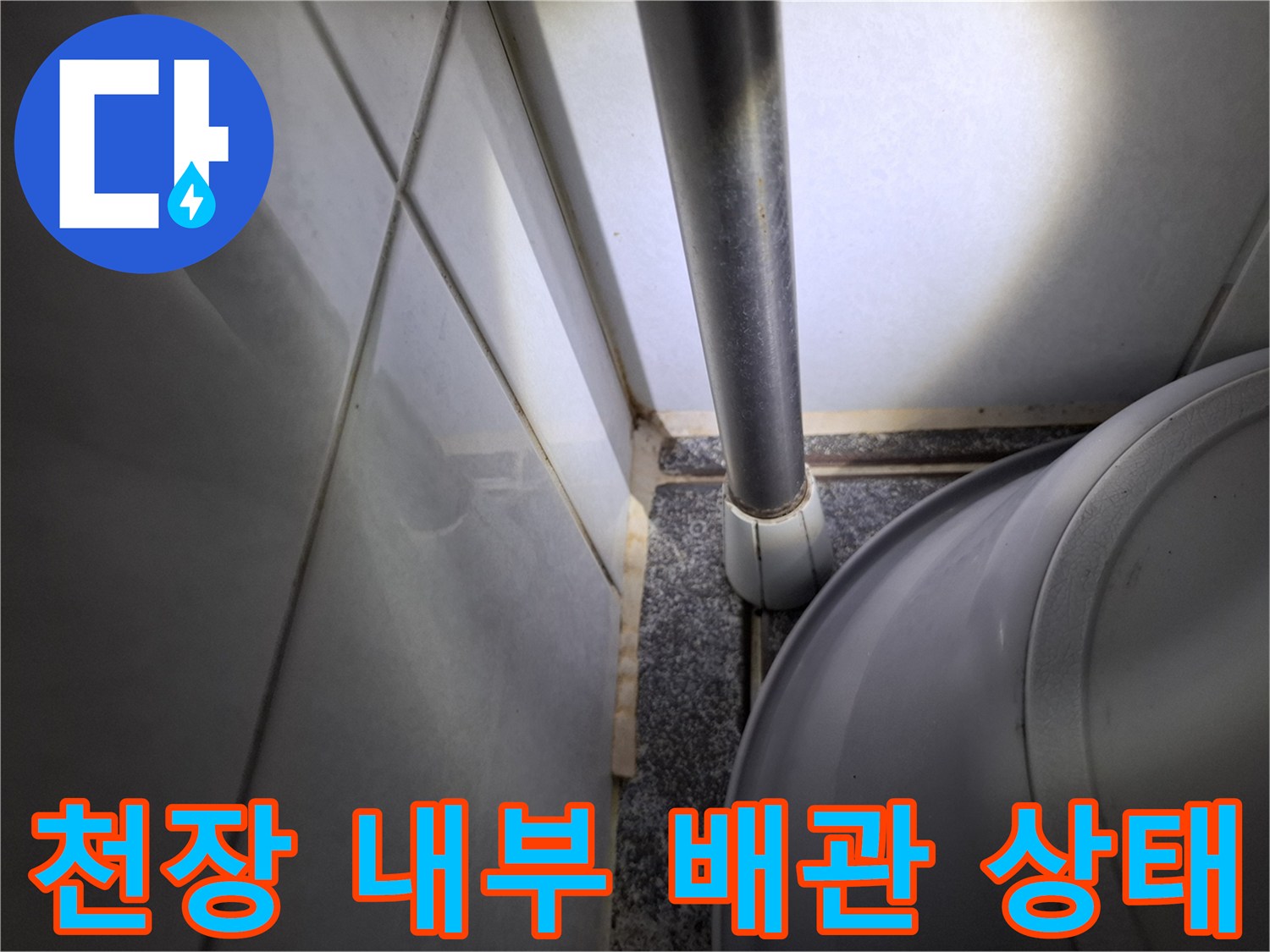화장실 천장 내부에 설치된 은색 배관과 타일 벽면 사진