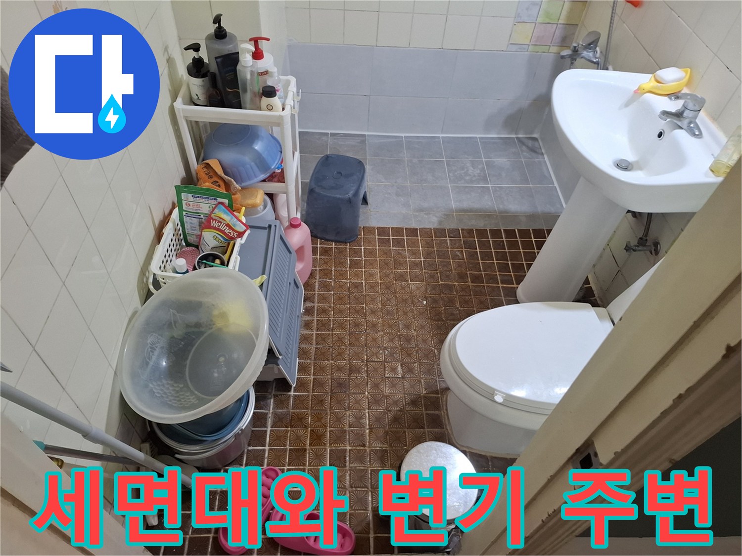 화장실 내 세면대 하부와 변기가 배치된 욕실 바닥 타일 전경입니다.