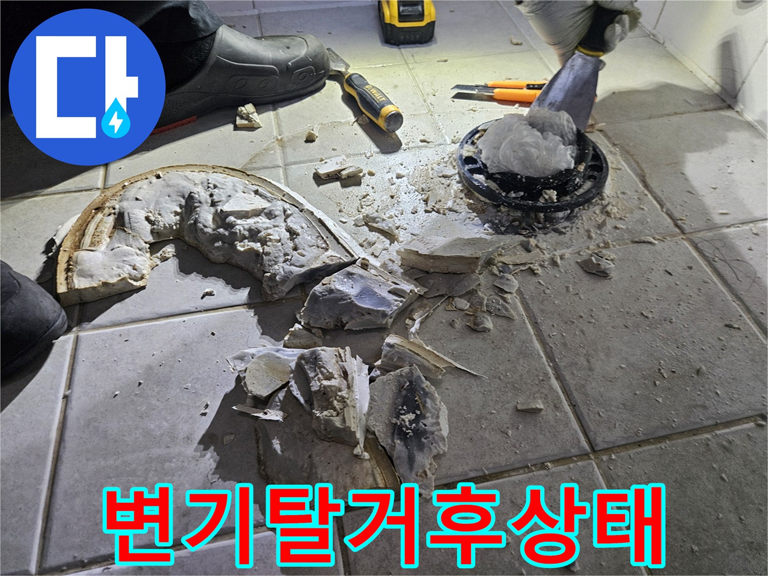 변기 탈거 후 드러난 배관 주변의 깨진 타일과 작업 도구입니다.