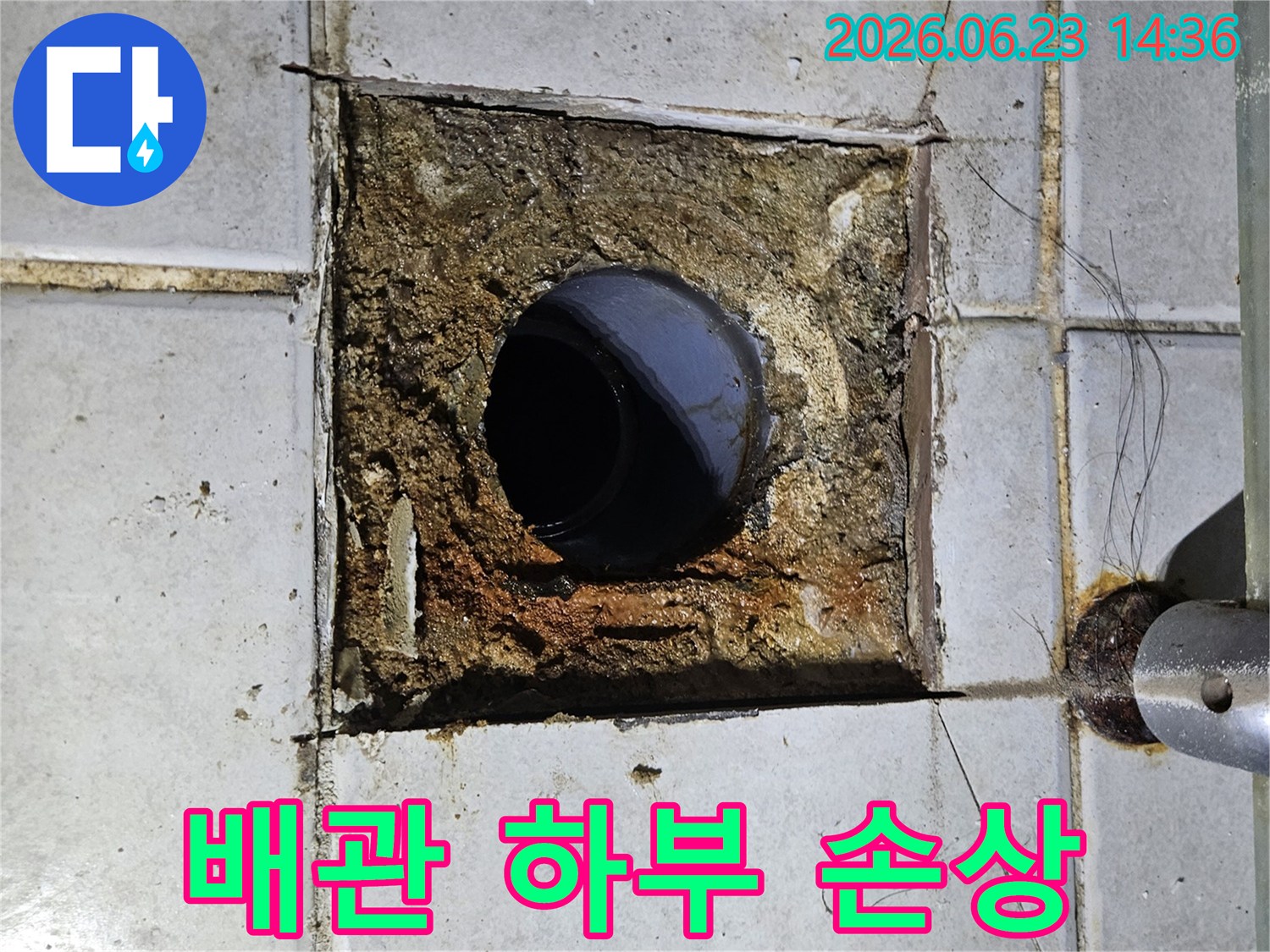 욕실 배관 하부의 구조물이 누수로 인해 심하게 손상되고-주변 타일이 파손된 모습