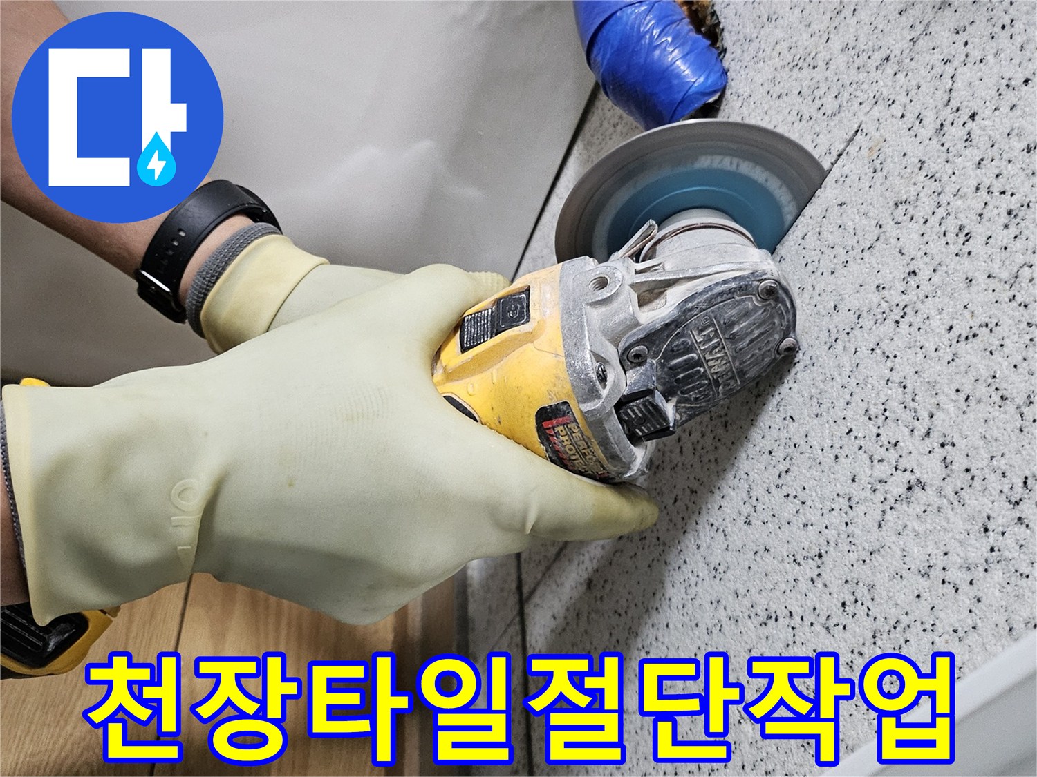 안전 장갑을 착용한 작업자가-그라인더로 천장 타일을-조심스럽게 절단하고 있습니다.