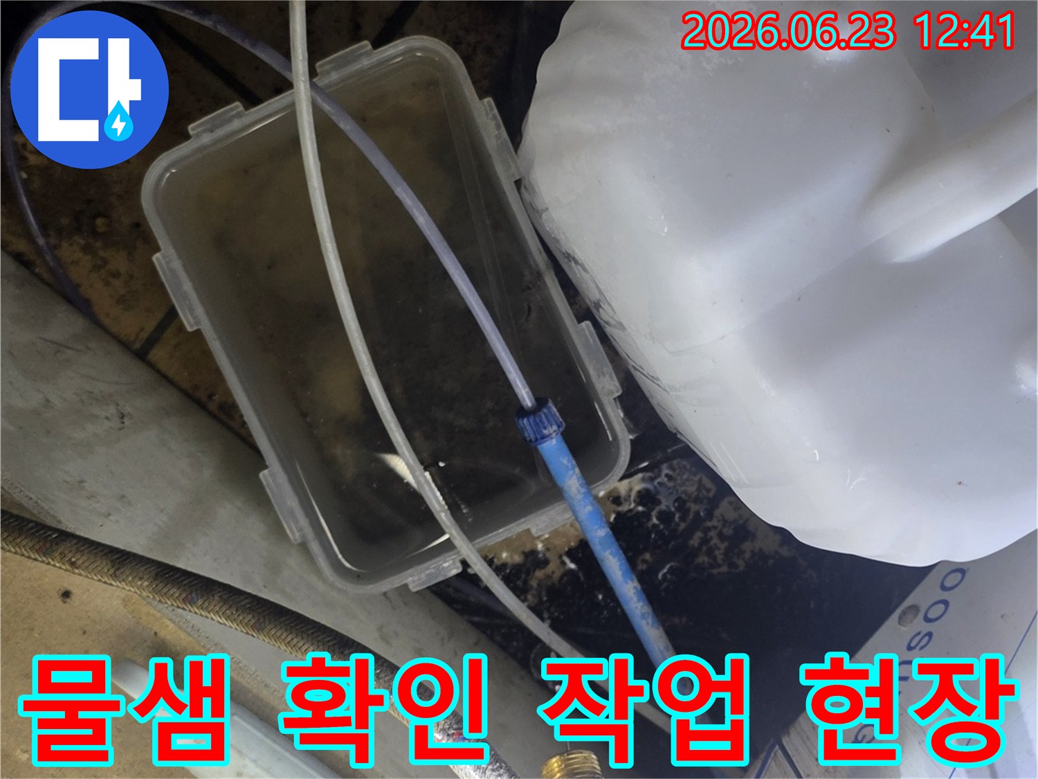 엔지니어가 누수 원인을 찾기 위해-새는 물을 투명 용기에 모으고 있는 현장 사진입니다