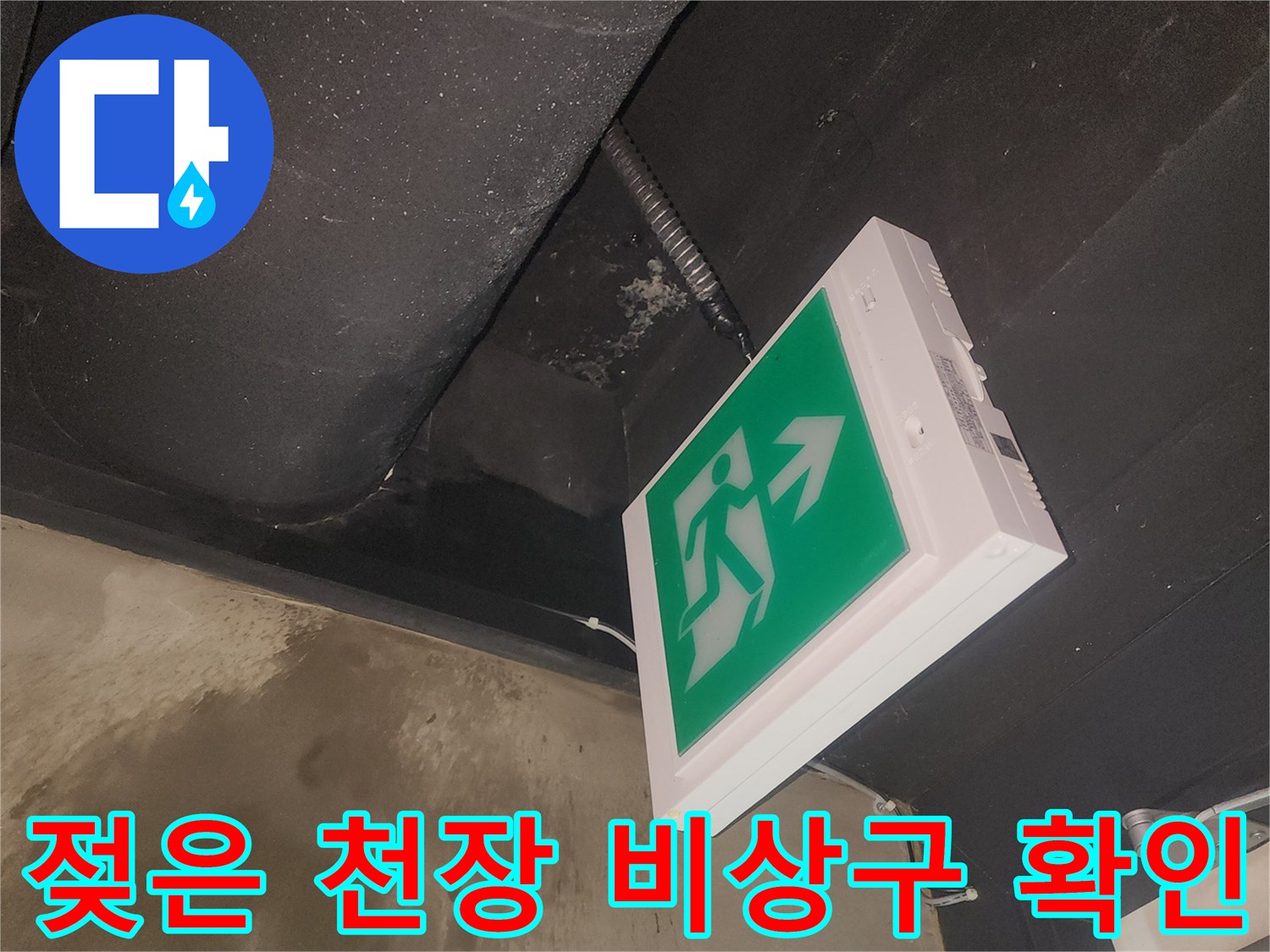 건물 천장에서 발생한 물샘 현장을-비상구 등기구와 함께 촬영한 이미지입니다