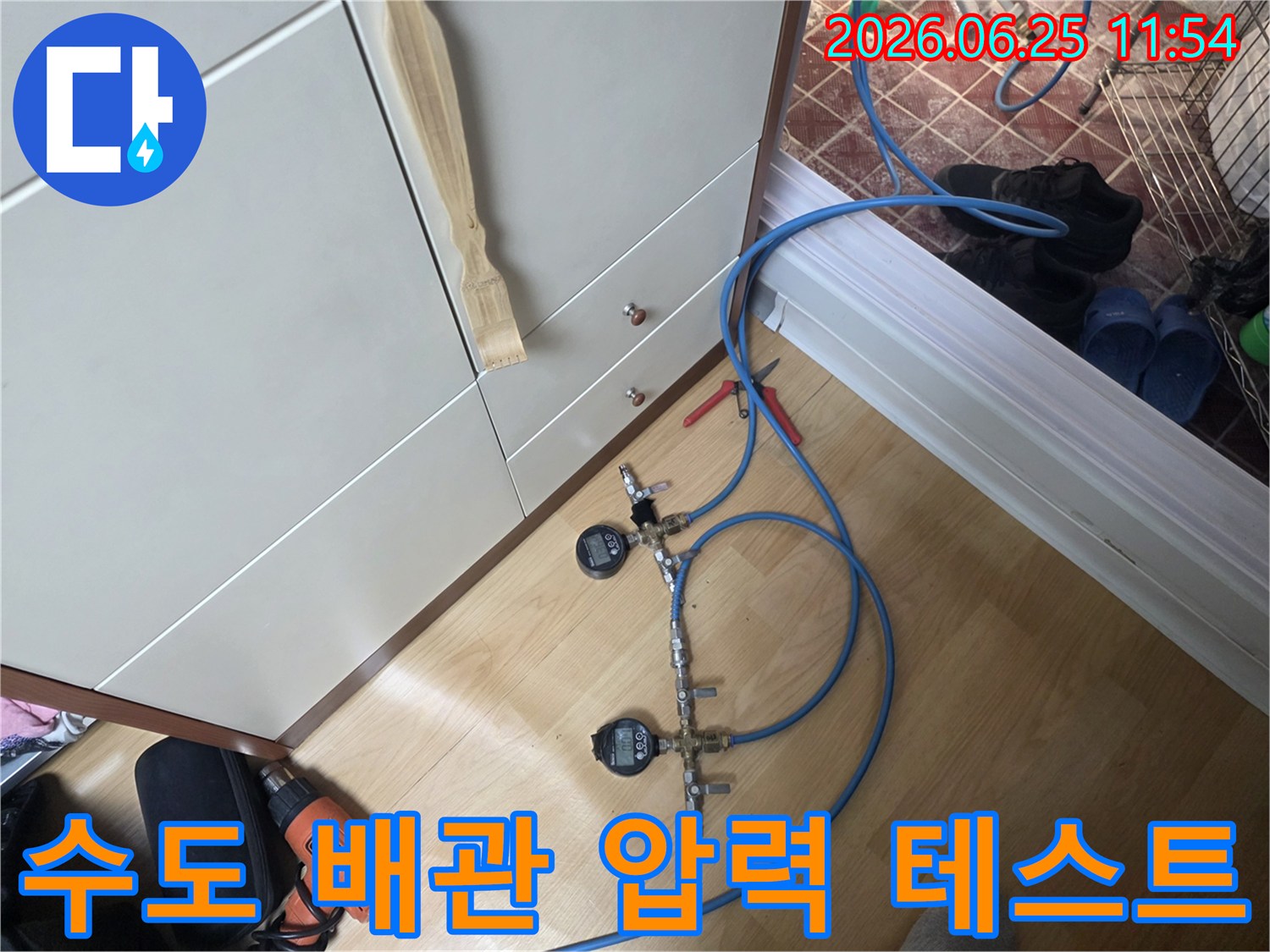 누수 엔지니어가 수도 배관의 누수 여부를 확인하기 위해 디지털 압력 게이지가 연결된 가압 테스트 장비를 설치하고 있습니다