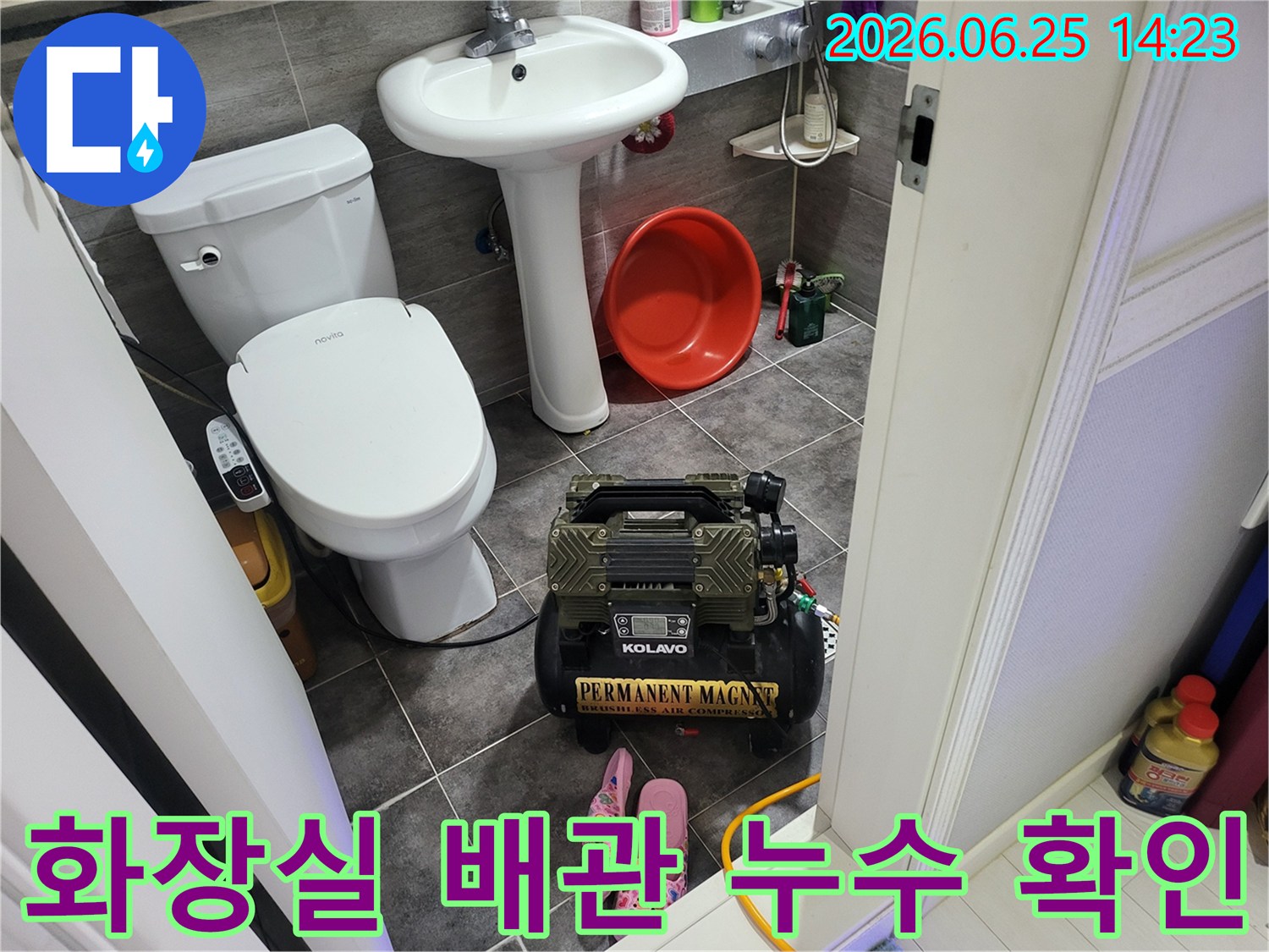 변기와 세면대 옆에 놓인-누수 탐지용 콤프레셔 장비가-작동 대기 중인 욕실 풍경