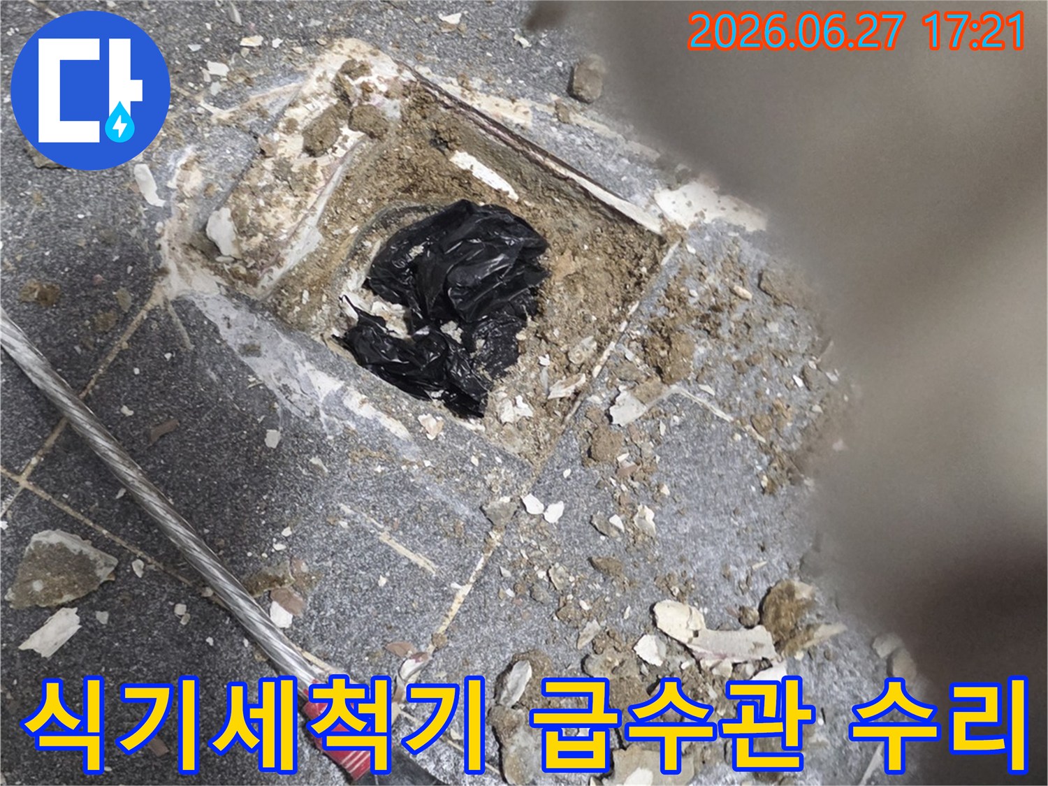 이 이미지는-주방 식기세척기 하부에서 발생한 누수로 인해-급수관 연결 부위를 점검하고-수리하는 작업 현장입니다.