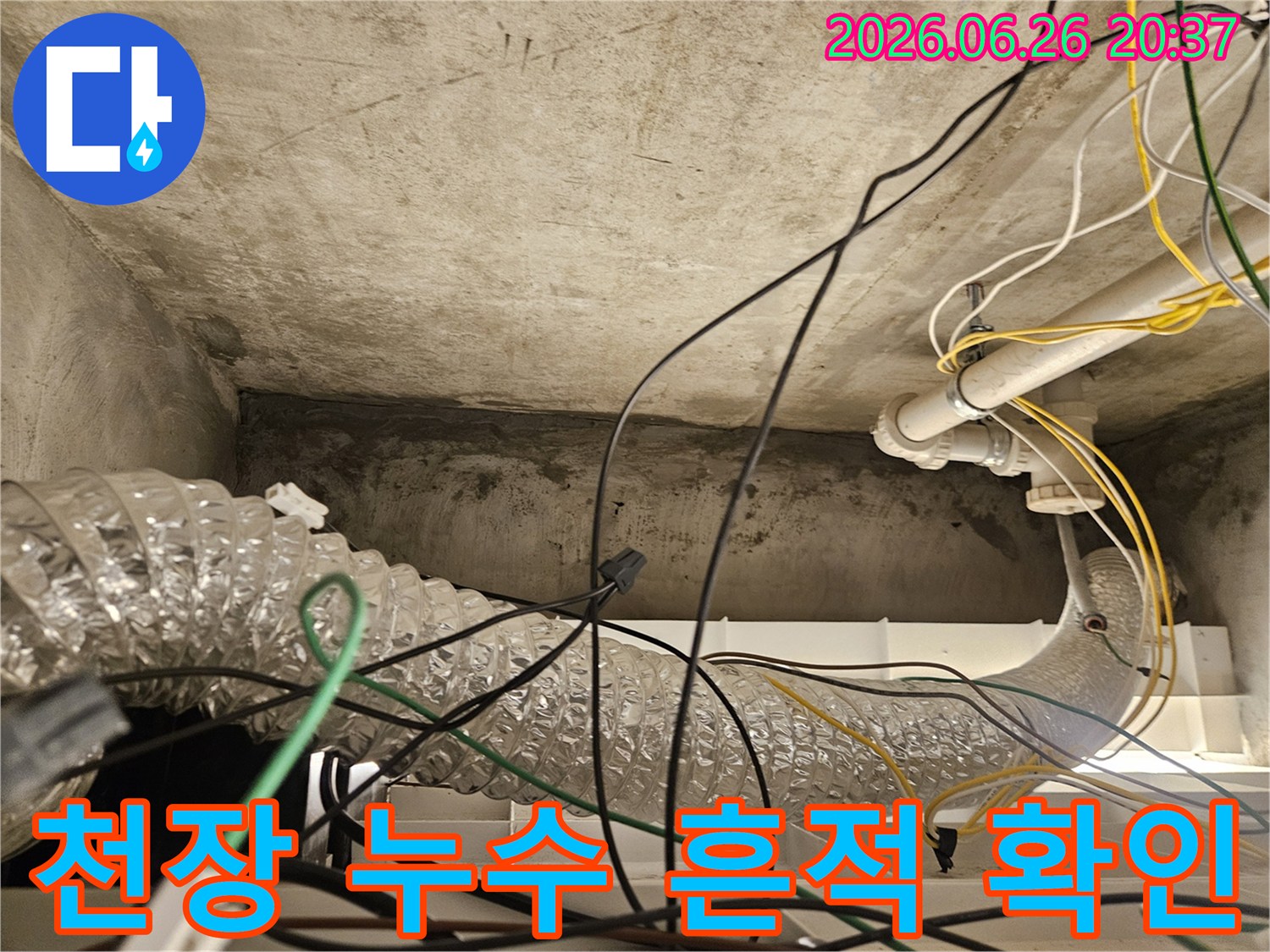 이 이미지는 복잡하게 얽힌 배선과-환기 덕트-그리고 천장 콘크리트 구조물에서 발생한-누수 흔적을 보여줍니다.
