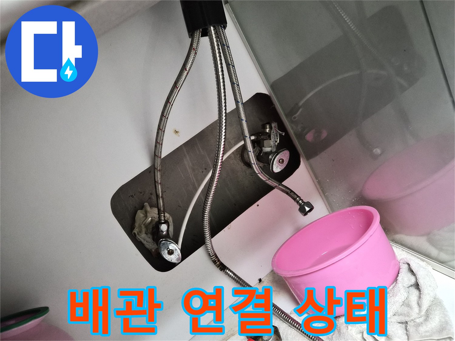 싱크대 하부 배관과 공구가 놓인 작업 현장 사진